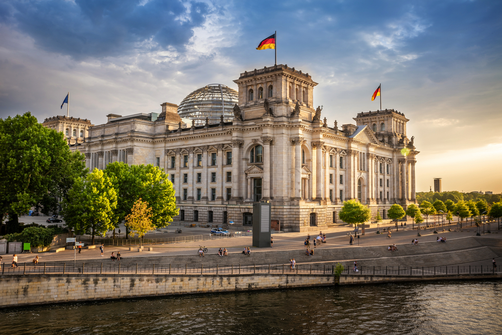 Reichstagsgebäude in Berlin bei Sonnenuntergang mit deutschen Flaggen.